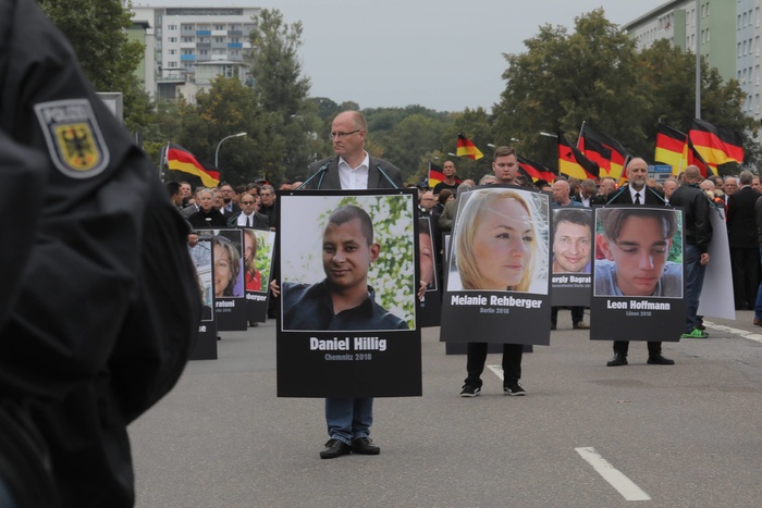 Протестующие несут портреты граждан Германии, убитых мигрантами.